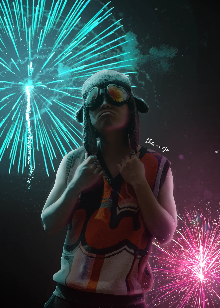 A guy in goggles and a winter hat surrounded by fireworks